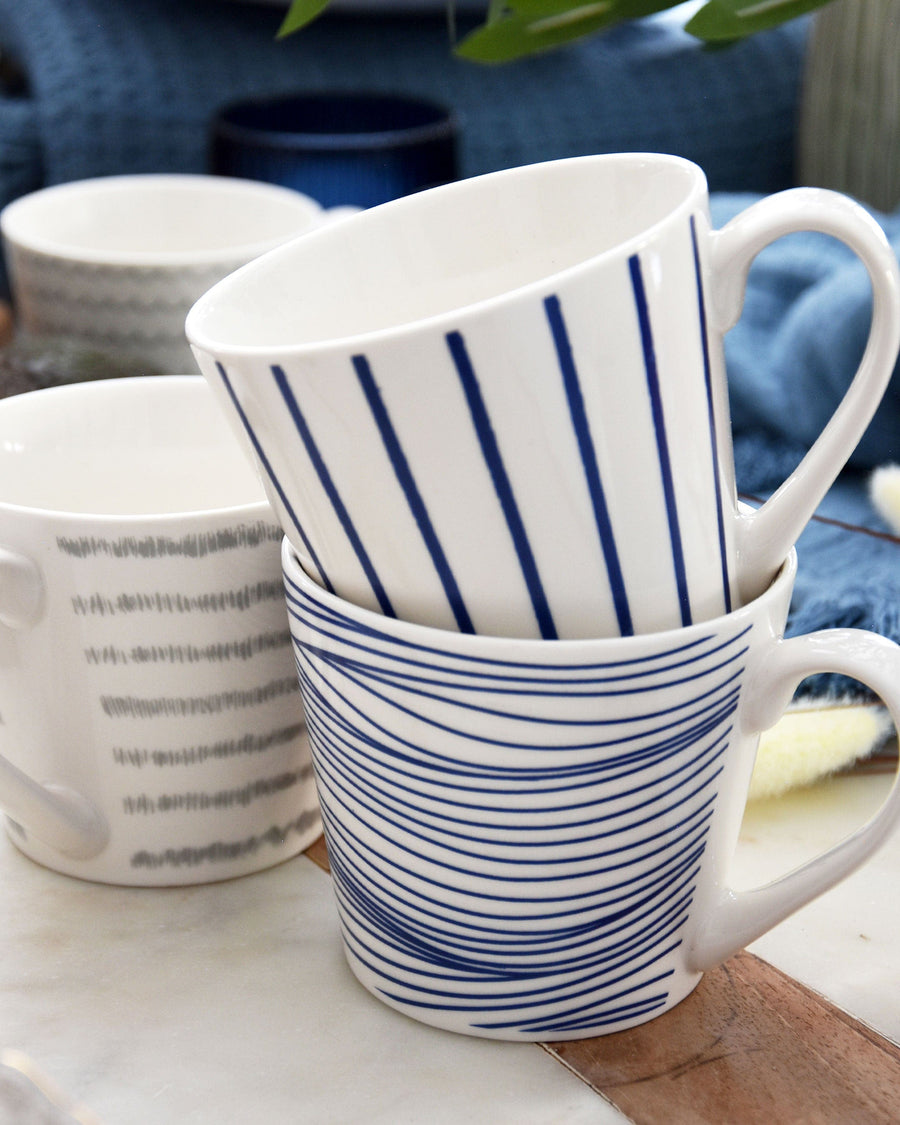 Image of a Nautical Blue Lined Wide Mug featuring horizontal navy stripes against a white background, with a sturdy handle on the side for a comfortable grip. The mug conveys a maritime theme ideal for a coastal-inspired kitchen.