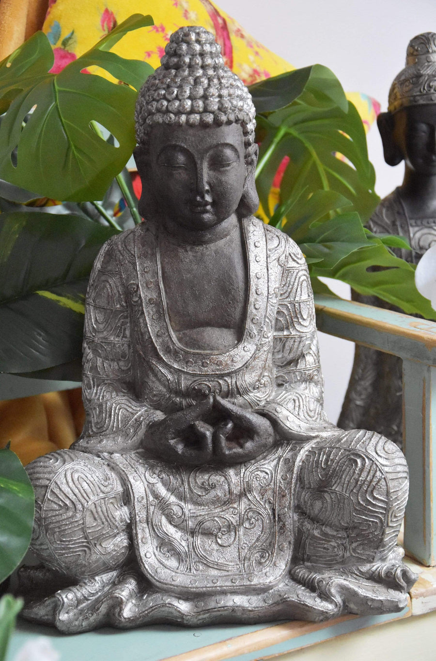 Sitting Buddha Ornament Black and Silver Large  outside in garden with artificial plants and 